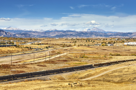 Autumn rural landscape with cargo train and Rocky Mountains in distance, Colorado, USA.の写真素材