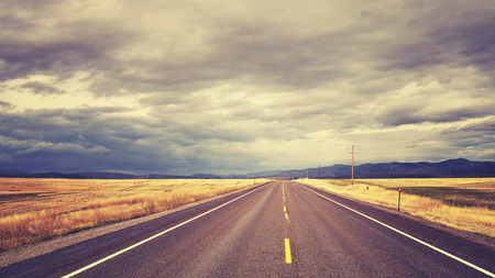 Vintage toned countryside road with rainy clouds,USA.の写真素材