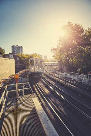 Vintage stylized train entering platform against rising sun in Chicago city, USA.