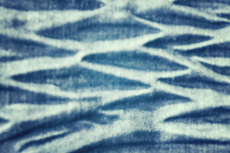 Color toned blurred close up picture of blue wrinkled jeans fabric, abstract background.の写真素材