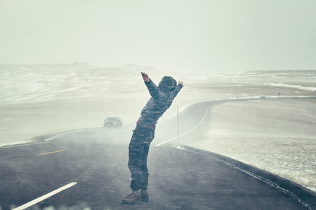 Woman tries to stand against snow flurry seen through a windshield, color toning applied.の写真素材