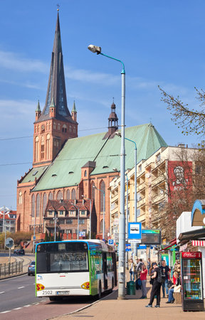 Szczecin, Poland - April 01, 2017: Bus stop with waiting people at Wyszynskiego street, Cathedral Basilica of St. James the Apostle in background.のeditorial素材