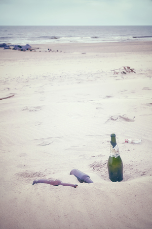 Color toned picture of empty liquor bottles left on a beach, environmental pollution concept picture. の写真素材