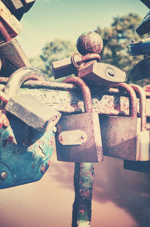 Retro stylized picture of old rusty padlocks on a bridge, love symbol, shallow depth of field.の写真素材