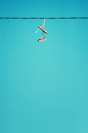 Pair of old shoes hang on wire, color toning applied, copy space.の写真素材