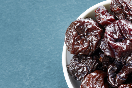 Dried plums in a bowl, shallow depth of field, space for text.の写真素材