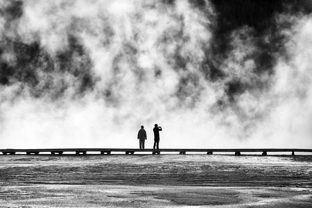 Silhouettes of tourists on a footbridge at steamy Grand Prismatic Spring, Yellowstone National Park, Wyoming, USA.の写真素材