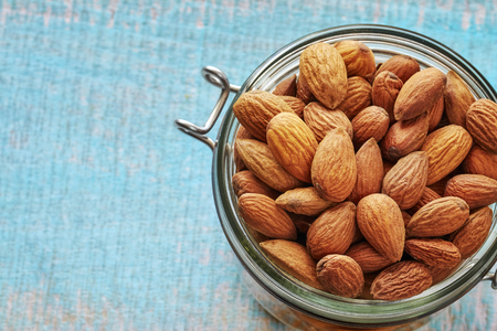 Almonds in a jar on a rustic wooden background, space for text, shallow depth of field.の写真素材
