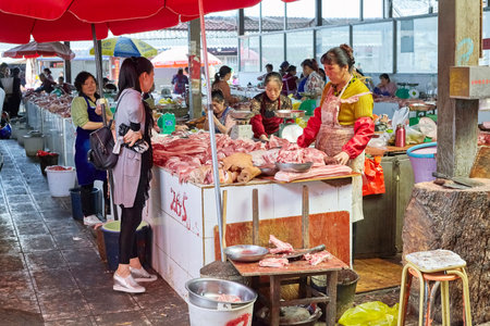 Lijiang, Yunnan, China - September 27, 2017: Customer chooses fresh meat at the local market. China consumes around 28% of the world's meat, half of it is pork.のeditorial素材