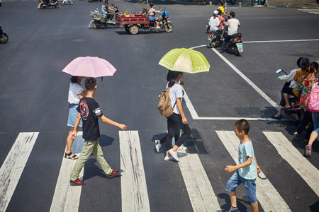 Guilin, China - September 15, 2017: Women with sun umbrellas cross street in downtown Guilin.のeditorial素材