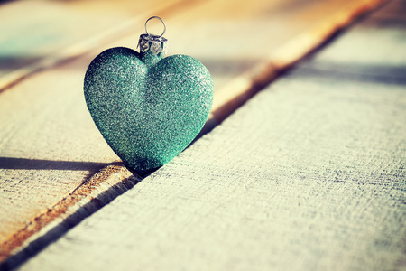 Christmas green bauble heart on a wooden background, color toned photo, selective focus.の写真素材