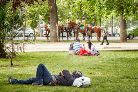 Santiago de Chile, Chile - October 24, 2013: People rest in a municipal park with mounted police in a distance (Carabineros de Chile).のeditorial素材