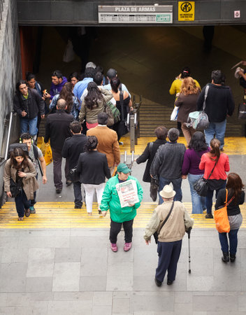 Santiago de Chile, Chile - October 24, 2013: People pass woman advertising La Segunda, Chilean afternoon daily newspaper, at the Plaza de Armas metro station entrance.のeditorial素材