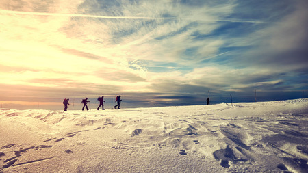 Winter mountain landscape with travelers silhouettes at sunset, color toned picture.の写真素材