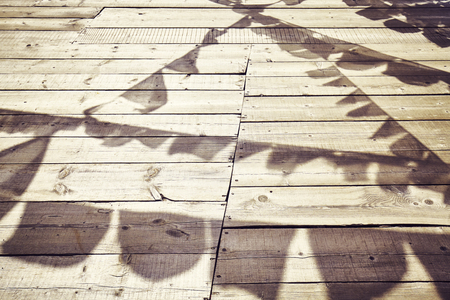 Shadows of Buddhist prayer flags on a wooden floor, color toned conceptual background.の写真素材