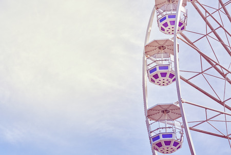 Retro toned picture of a Ferris wheel in an amusement park.