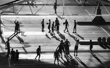 Basketball players silhouettes on Brooklyn pier court at sunset, New York City, USA.の写真素材