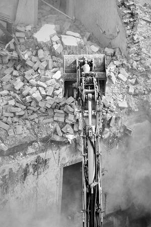 Building demolition with an excavator in dust cloud, view from above.