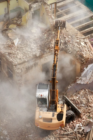 Building demolition with an excavator in dust cloud, view from above.の写真素材
