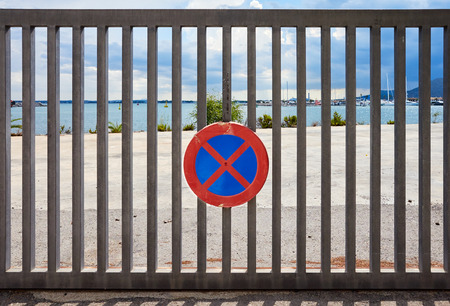 No stopping, no standing and no parking anytime sign on a steel fence, marina in background.の写真素材