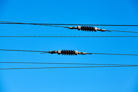 Overhead train electric traction system against the blue sky.