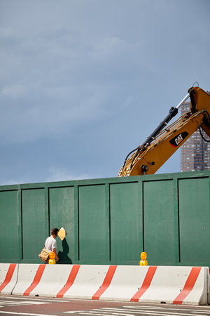 New York, USA - June 28, 2018: Man looks through a provisional fence window at a construction site in Downtown Manhattan.のeditorial素材