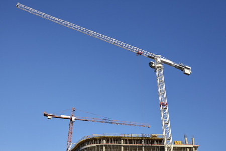 Construction site cranes against the blue sky.の写真素材