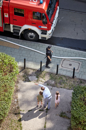 Szczecin, Poland - July 19, 2018: Man shows children a fire brigade that prepares to extinguish residential building fire at Niemierzynska Street.のeditorial素材