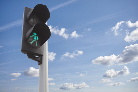 A traffic green light for pedestrians against the sky.の写真素材
