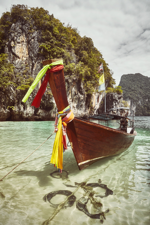 Retro toned picture of a long tail boat moored by a tropical island, Thailand.の写真素材