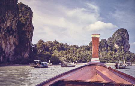Wooden boat bow with tropical island in background, color toned picture, Thailand.の写真素材