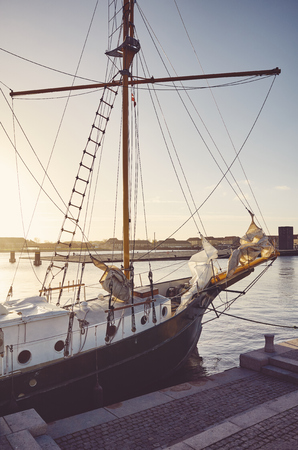 Old schooner moored to a pier in Copenhagen at sunset, color toning applied, Denmark.の写真素材
