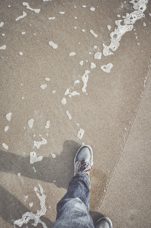 Walking on a beach, top view of legs and shoes, color toning applied.の写真素材