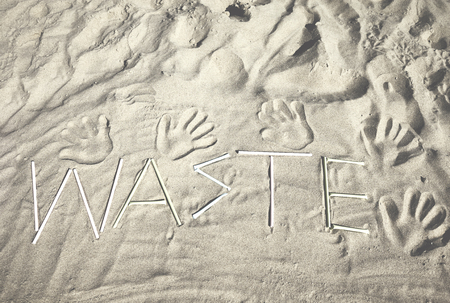 Waste word made of plastic straws on sand, retro color toned picture.の写真素材