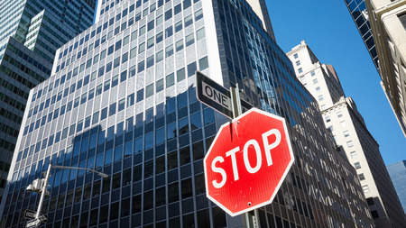 Stop sign on a street of New York City, modern buildings in background, USA.