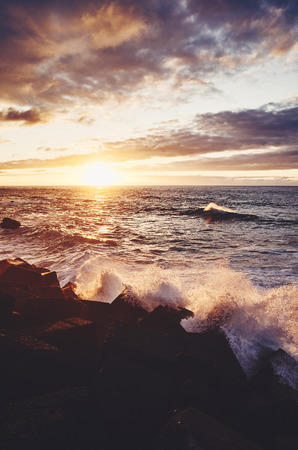 Scenic sunset with waves crashing on rocks, color toning applied, Puerto de la Cruz, Tenerife, Spain.の写真素材