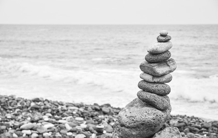 Black and white picture of a stone stack on a beach, selective focus.の写真素材