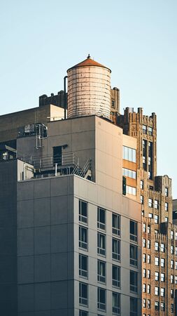 Retro toned picture of a water tower on a rooftop at sunset, New York City, USA.の写真素材