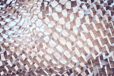 Abstract background made of perforated brown paper, selective focus, color toning applied.