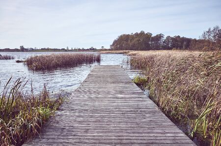 Retro toned picture of a wooden pier by lake in Autumn.の写真素材