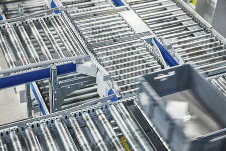 Transportation line conveyor roller with container in motion, selective focus.
