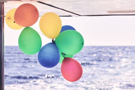Colorful party balloons on a boat, color toning applied.の写真素材