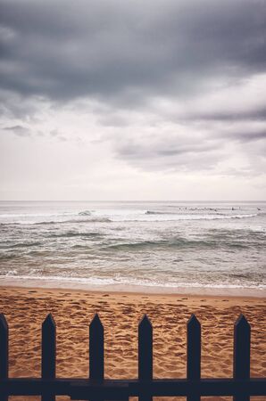 Beach behind wooden fence on a rainy day, color toned picture.の写真素材