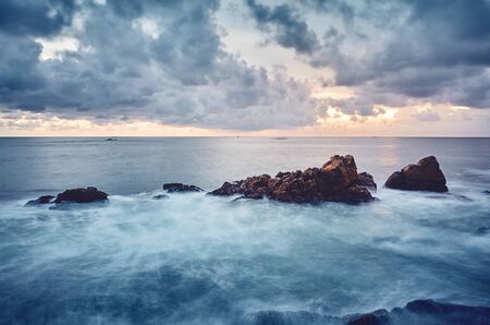 Rocky coast at sunset, color toned long exposure picture, Sri Lanka.