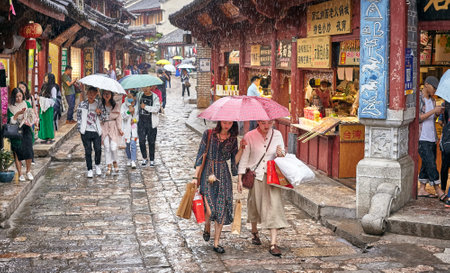 Lijiang, China - September 22, 2017: People on the street of Old Town on a rainy day. Old Town of Lijiang was included in the UNESCO World Cultural Heritage list in December 1997.のeditorial素材