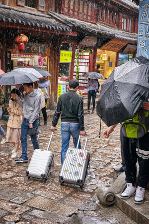 Lijiang, China - September 22, 2017: Tourists on the street of Old Town on a rainy day. Old Town of Lijiang was included in the UNESCO World Cultural Heritage list in December 1997.のeditorial素材