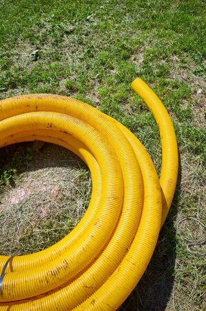 Yellow coil land drainage pipe on the ground, used to remove excessive water from fields and gardens.の写真素材