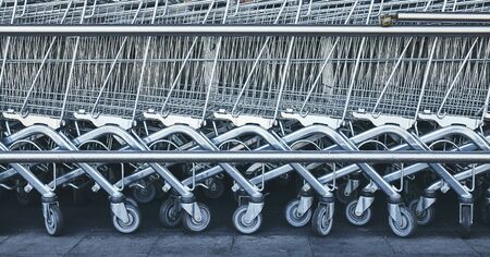 Row of empty shopping carts, color toning applied.