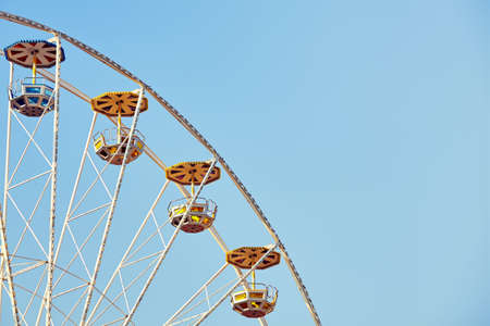 Retro toned picture of a Ferris wheel with cloudless sky, space for text.