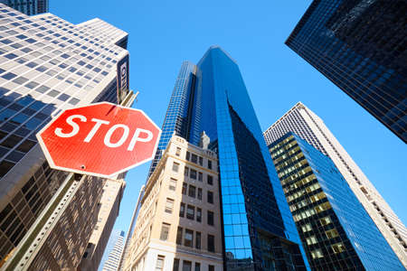 Looking up at stop sign on a street of New York City with modern buildings in background, selective...